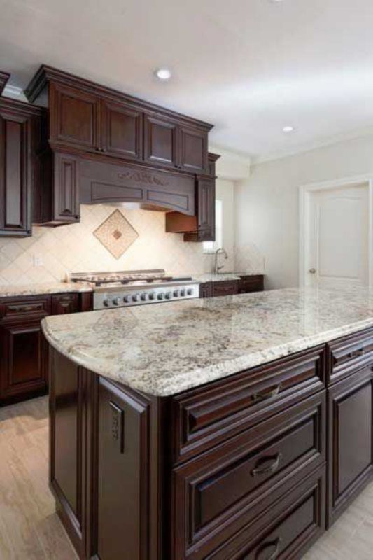 A kitchen with a large island and granite counter tops.