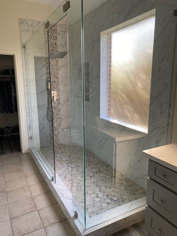 A bathroom with a walk in shower and a window.