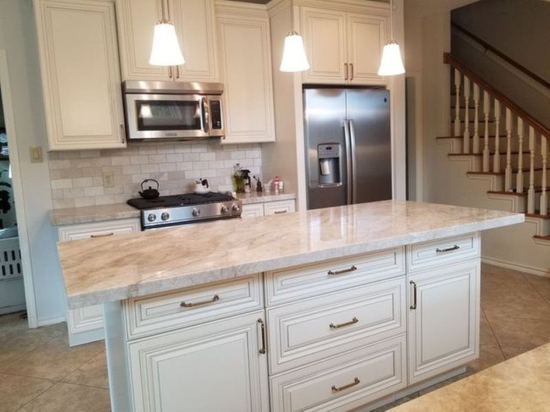 A kitchen with white cabinets , stainless steel appliances and a large island.