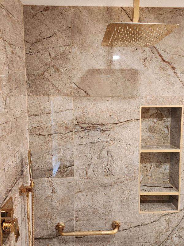 A bathroom with a shower head and a marble wall.