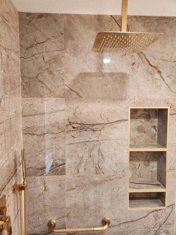 A bathroom with a shower head and a shelf.