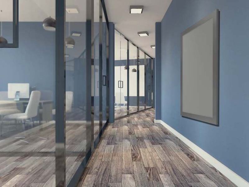 A hallway in an office with blue walls and wooden floors.