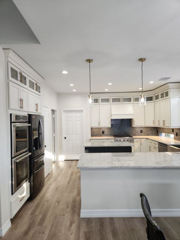 A kitchen with white cabinets , stainless steel appliances , and a large island.