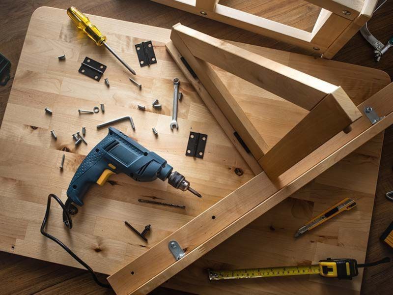 A drill is sitting on top of a wooden table.