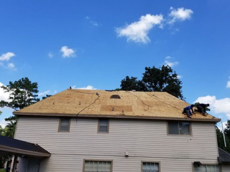 Two men are working on the roof of a house.
