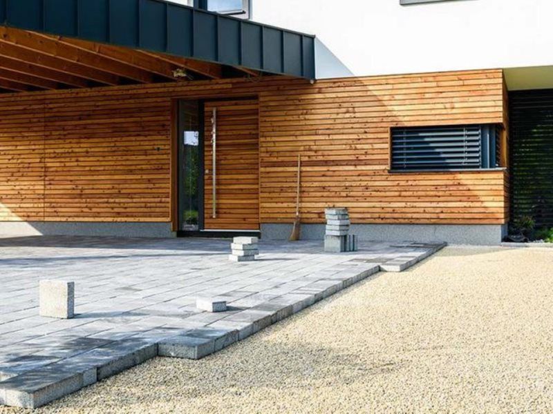 A house with a wooden facade and a concrete driveway in front of it.