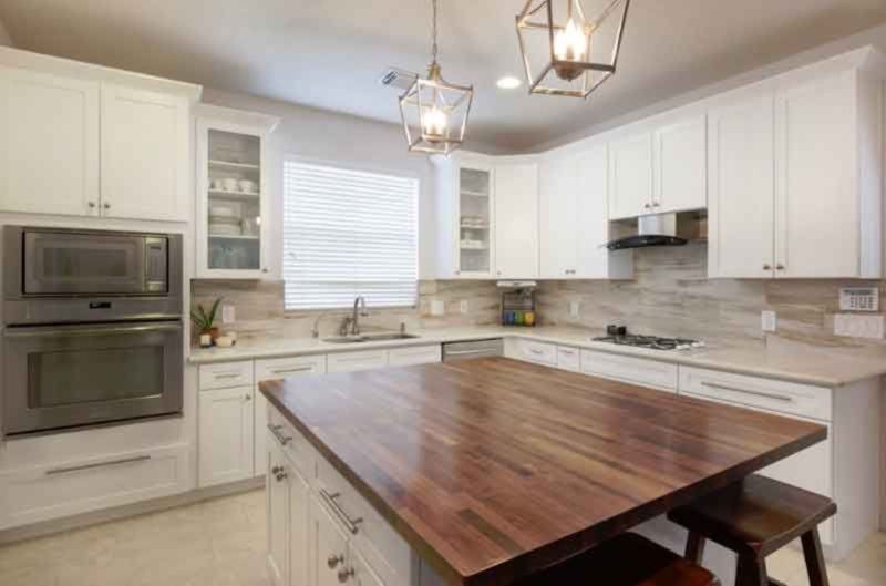 A kitchen with white cabinets and a large wooden island.
