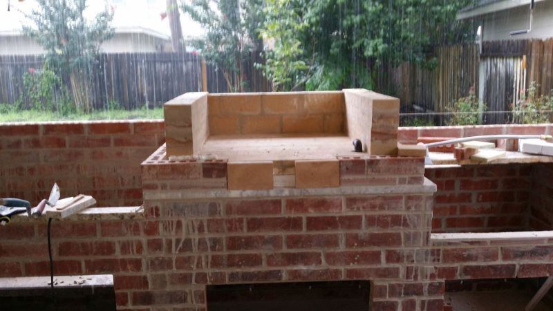A brick oven is being built in a backyard.