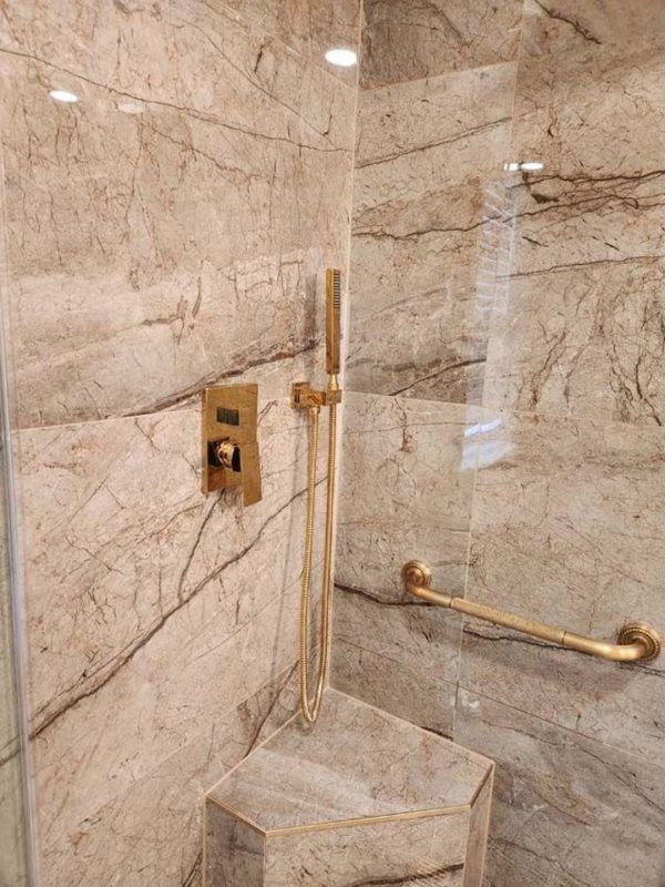 A bathroom with a walk in shower and a marble wall.