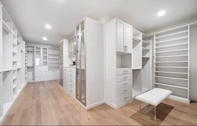 A walk in closet with lots of white cabinets and shelves.
