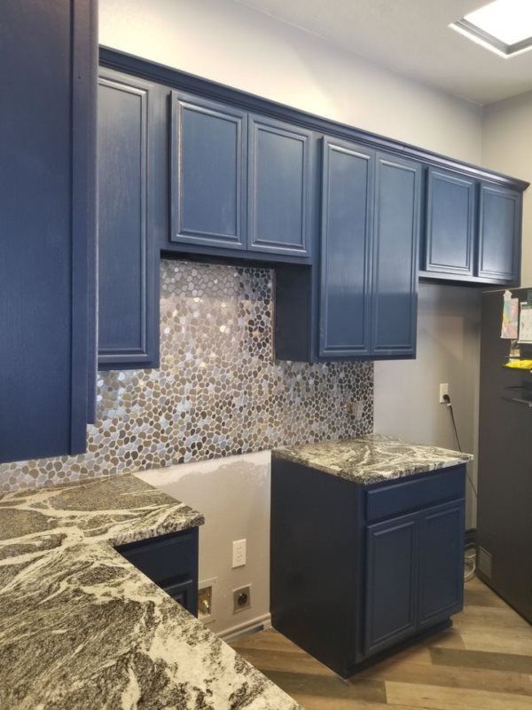 A kitchen with blue cabinets and granite counter tops.