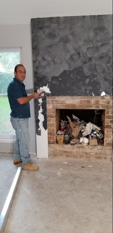 A man is standing in front of a fireplace in a living room.