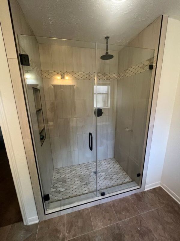 A bathroom with a walk in shower with a glass door.