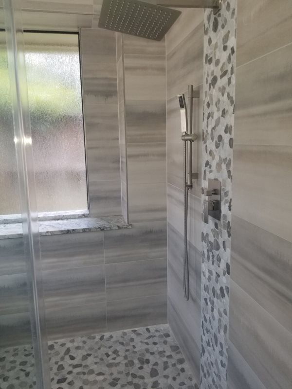 A bathroom with a walk in shower and a window.