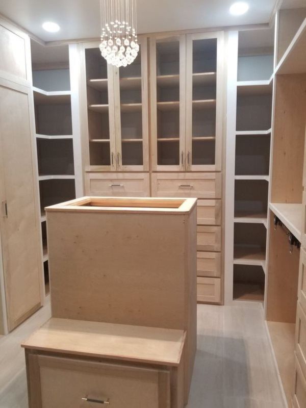 A walk in closet with lots of shelves and drawers