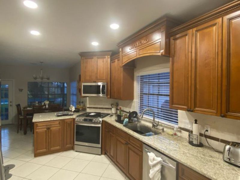A kitchen with wooden cabinets , granite counter tops , stainless steel appliances and a window.