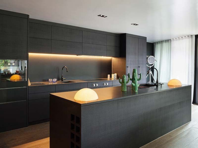 A kitchen with black cabinets and a large island in the middle