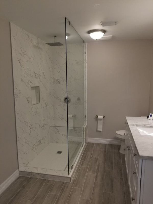 A bathroom with a walk in shower , sink and toilet.