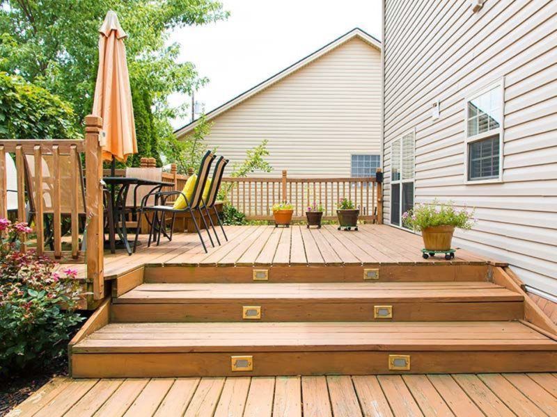 A wooden deck with stairs leading up to it in front of a house.