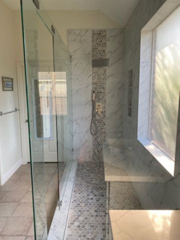 A bathroom with a walk in shower and a window