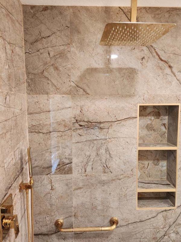 A bathroom with a shower head and a marble wall.