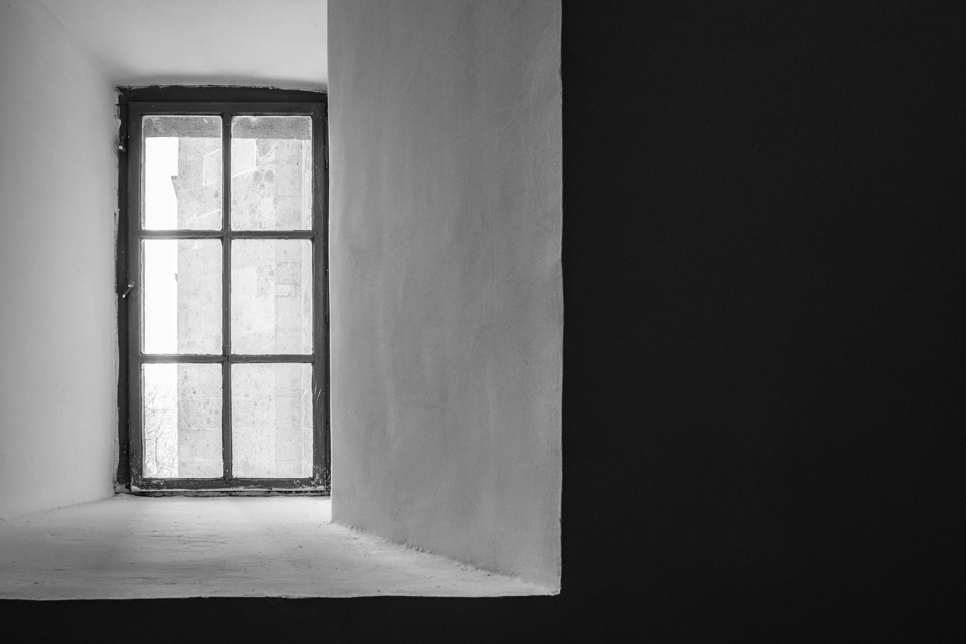 A black and white photo of an empty room with a window.