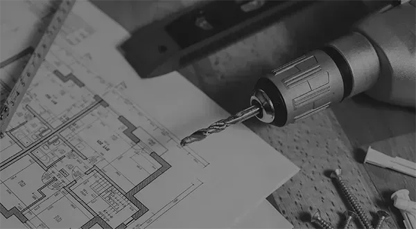 Ein Schwarzweißfoto einer Bohrmaschine, die auf einem Hausplan steht.