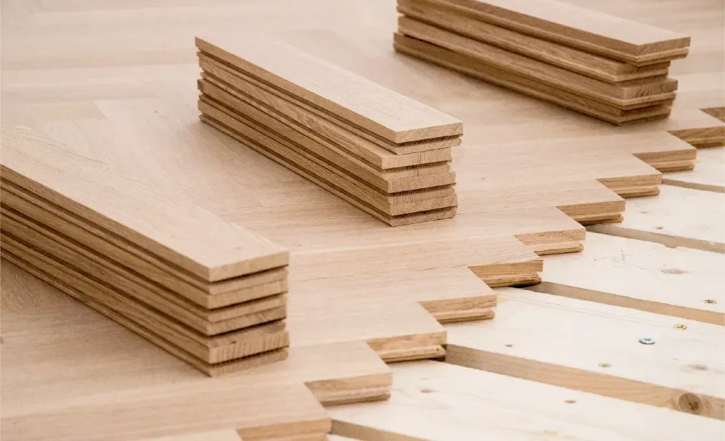 Ein Stapel Holzbretter, die übereinander auf einem Holzboden liegen.