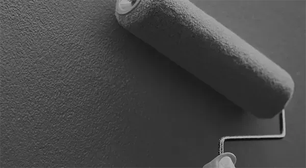 Eine Person streicht eine Wand mit einer Farbrolle.