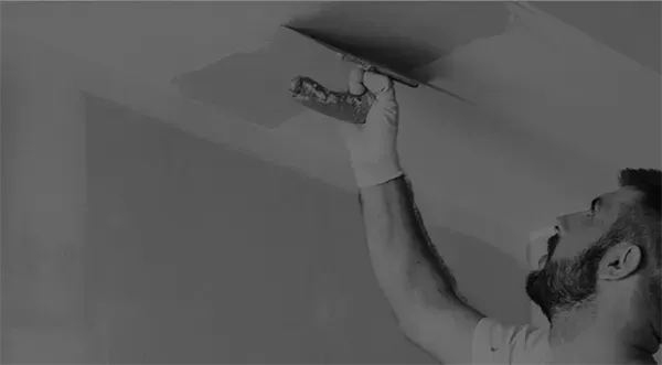 Ein Mann verputzt eine Decke mit einer Kelle.