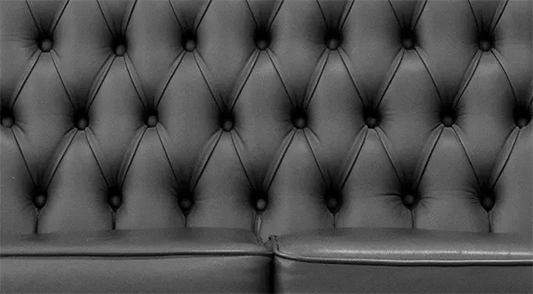 Ein Schwarzweißfoto eines gepolsterten Ledersofas.