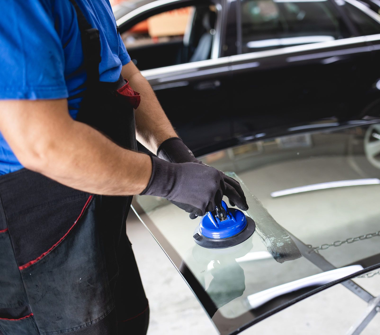 Mechanic using a suction cup tool to install a car windshield.