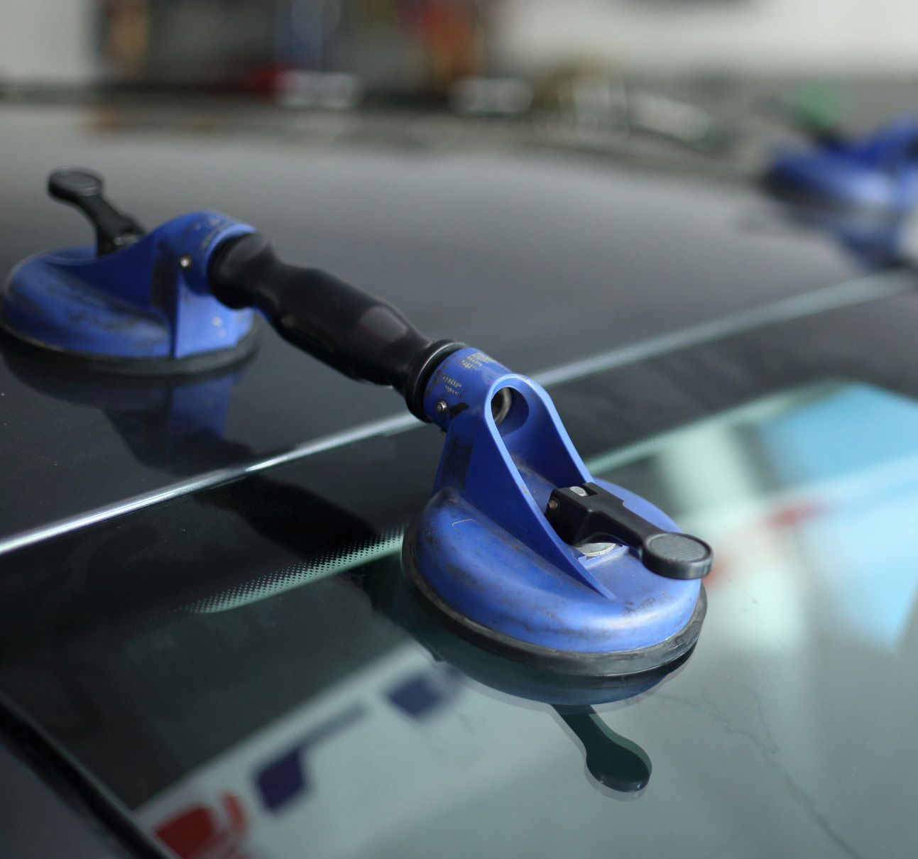 Blue suction cup tool on a glass surface, likely a car window.