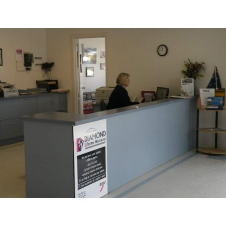 Reception desk with person working, clock on the wall, and waiting area behind.