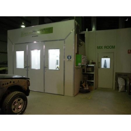 White paint booth and mixing room in a shop. A vehicle is partially visible.