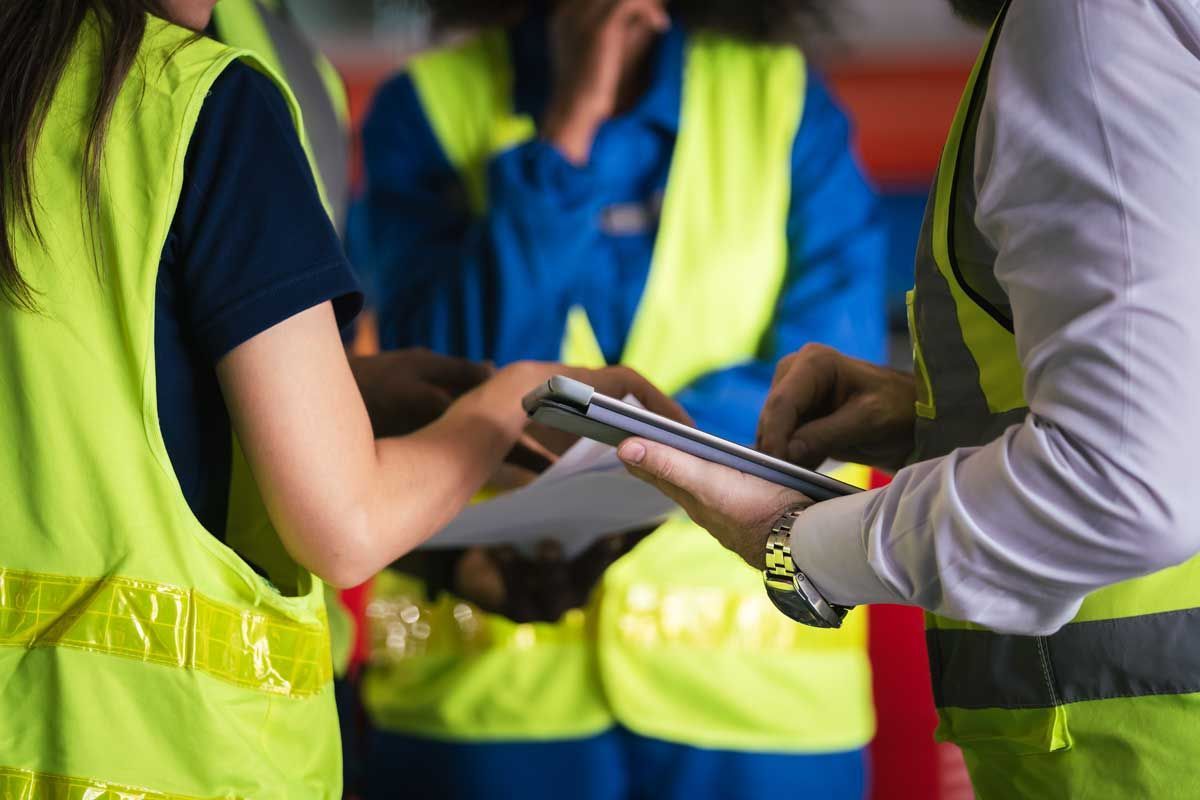Workers in safety vests review documents together.