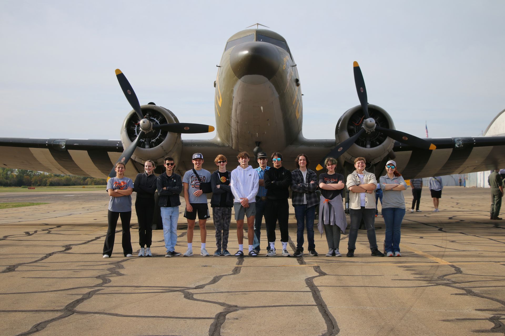 A group of high school students are standing in front of an airplane.