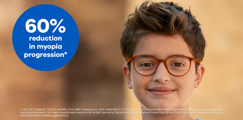 A boy wearing red glasses smiling at the camera with a blue circle containing the text ‘60% reduction in myopia progression*’ Image supplied by HOYA Lens UK