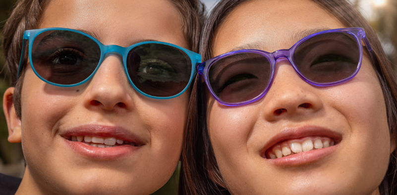 A boy and a girl wearing sunglasses as a visual representation of the MiYOSMART Sun lens options also available. Image supplied by HOYA Lens UK