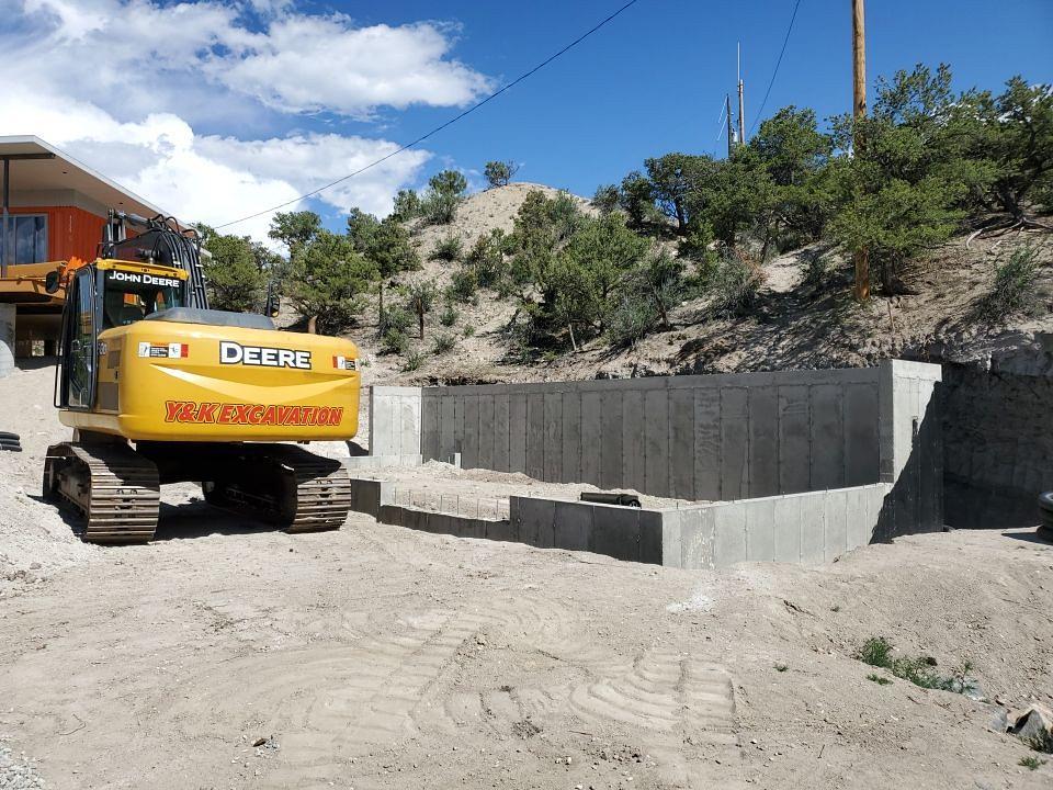 Excavator finishing dirtwork around foundation.