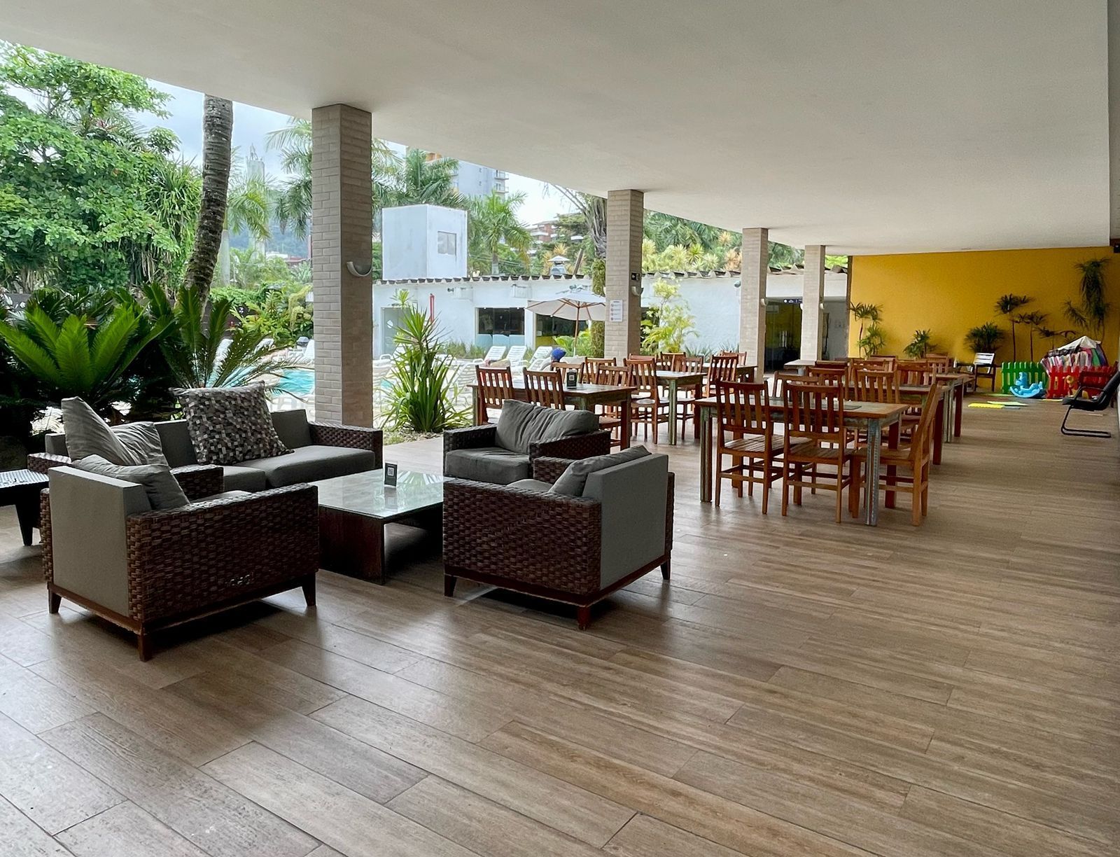 Pátio externo com áreas de estar e refeições sob um telhado.