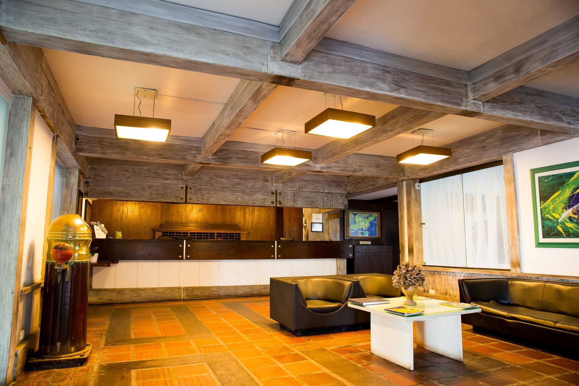 Hall de entrada do hotel com balcão de recepção, assentos e iluminação suspensa.