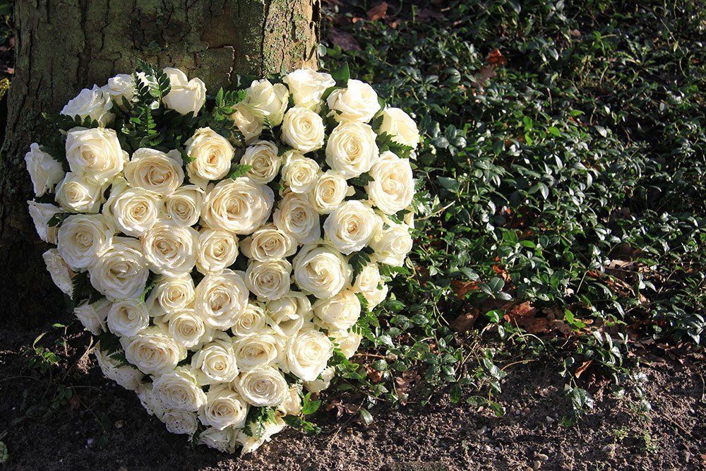 Un cuscino floreale a forma di cuore realizzato con rose bianche