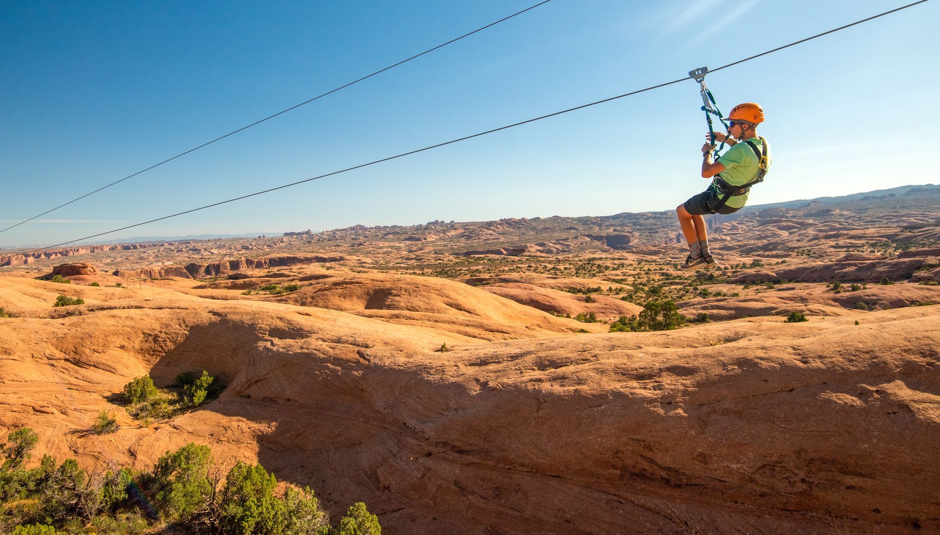 A guest rides the Moab zipline across sandstone fins.