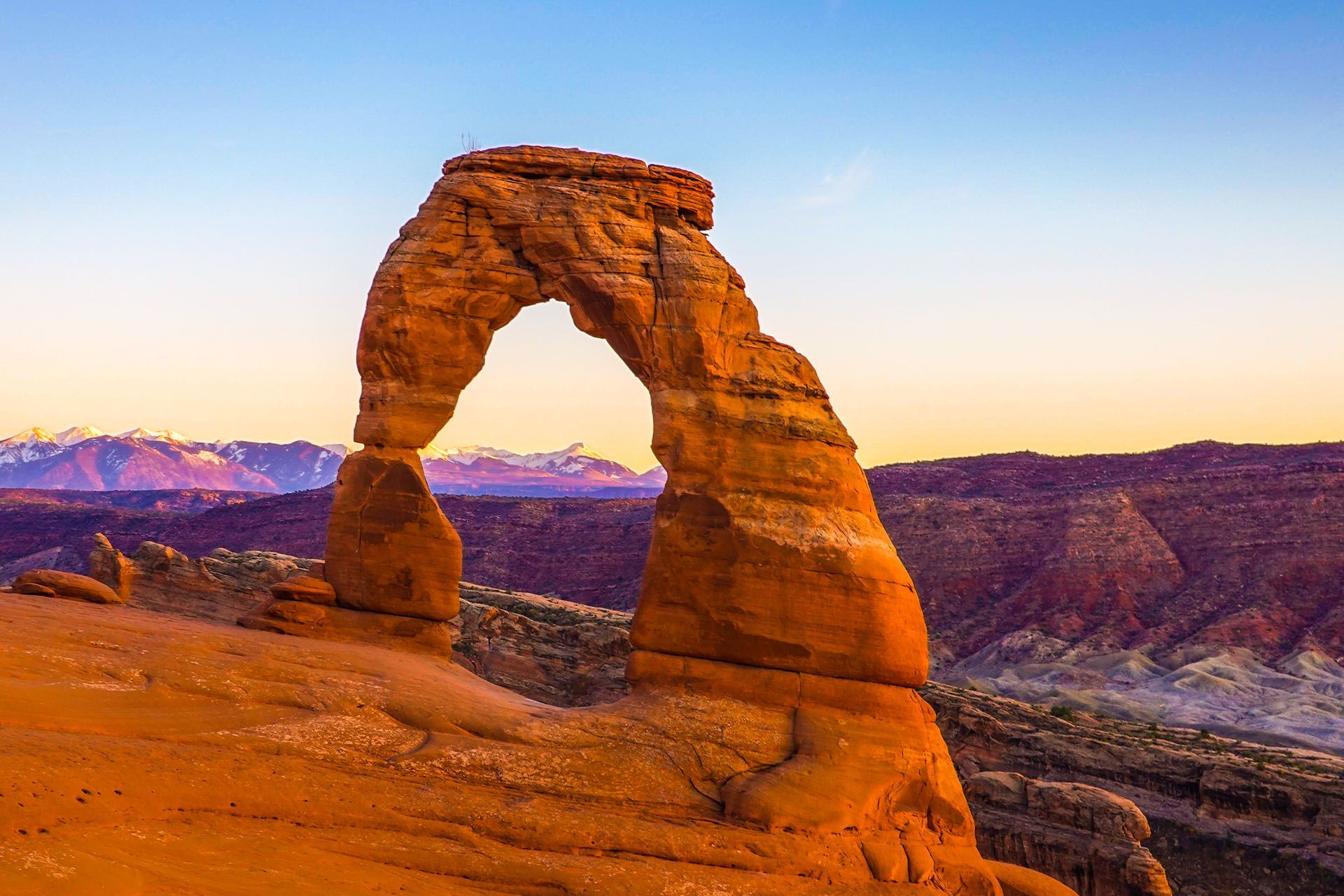 Delicate Arch in Arches National Park against a sunset sky.