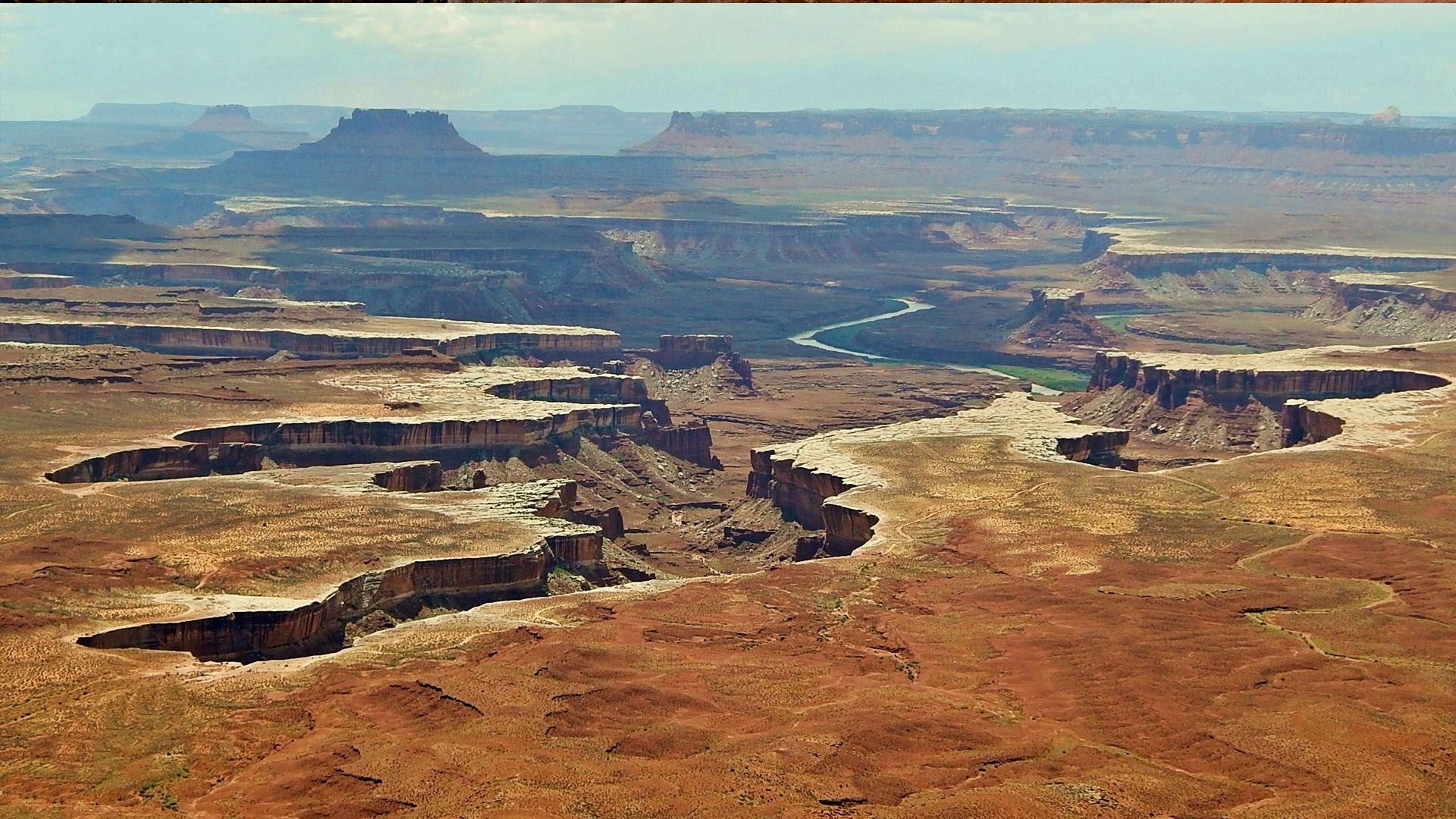 Canyonlands National Park in Utah. Red rock formations with river, blue sky and distant mesas.