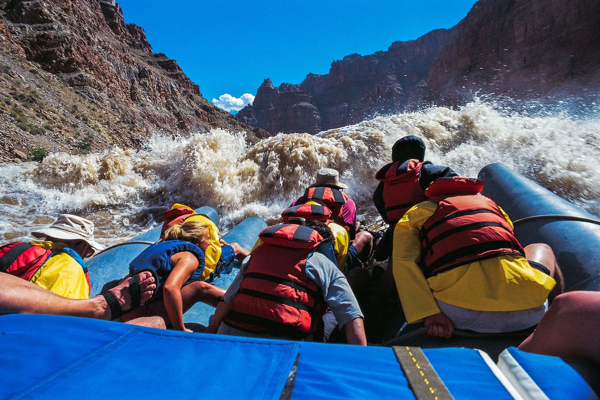 A group of people in life jackets are rafting down a river