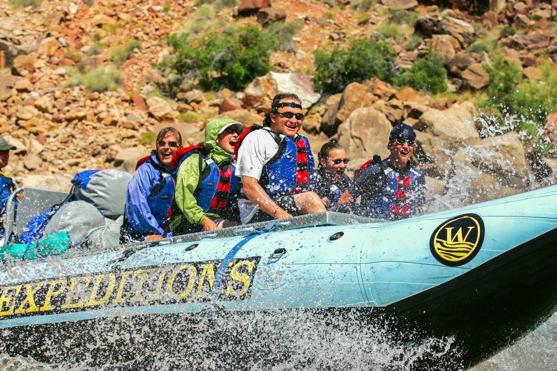 A group of people are in a raft that says expeditions on it
