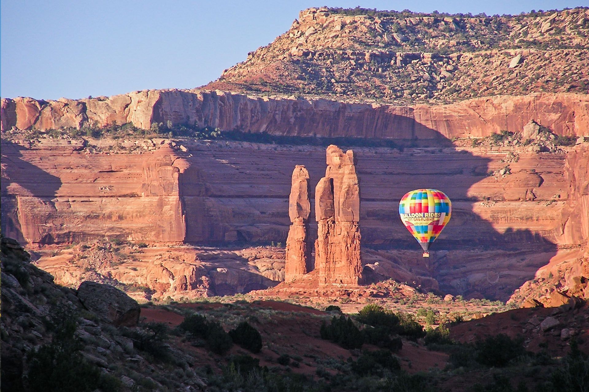 An aerial view of a colorful hot air balloon flying over a desert landscape.