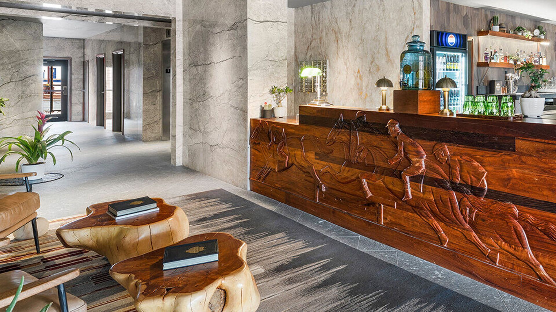 Hotel lobby with a wooden front desk, tree stump tables, and a bar.